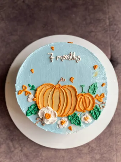 A lovely pumpkin-themed cake to celebrate a baby's 7th month birthday. The hand-piped pumpkins and flowers give it a charming, rustic feel.