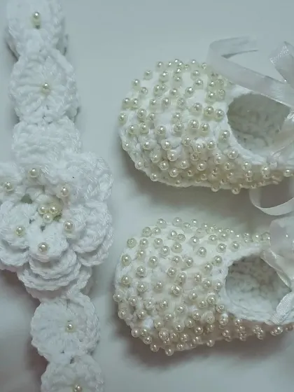 A different angle of the pearl-adorned booties and headband set, showing the intricate detail of the floral headband.