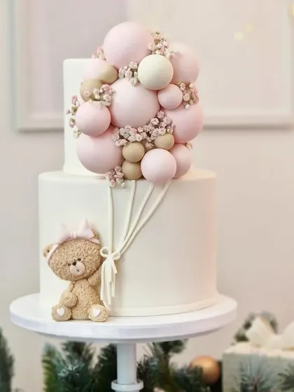 An adorable two-tiered teddy bear cake with a balloon bouquet.
