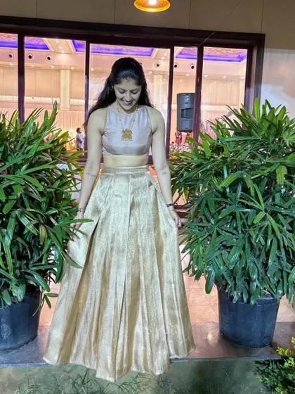 A young woman in a simple yet elegant gold lehenga set, perfect for a reception or festive occasion.