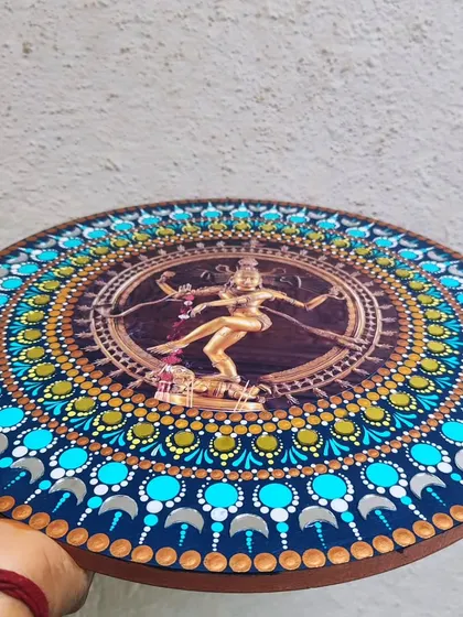 An angled view of the Nataraja dot mandala, showing the layers of colors and the shimmering effect of the small mirrors embedded in the design.