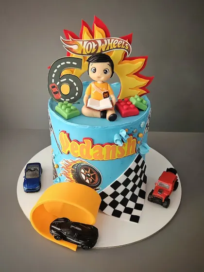 A revved-up Hot Wheels theme cake for Vedansh. This blueberry cake features a race track, Lego blocks, and a miniature of the birthday boy himself with his favorite book.