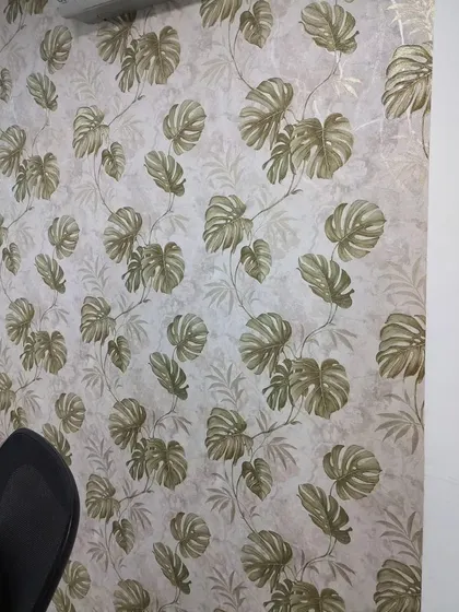 An office or study with a monstera leaf wallpaper. The botanical pattern can help create a more relaxed and productive work environment.
