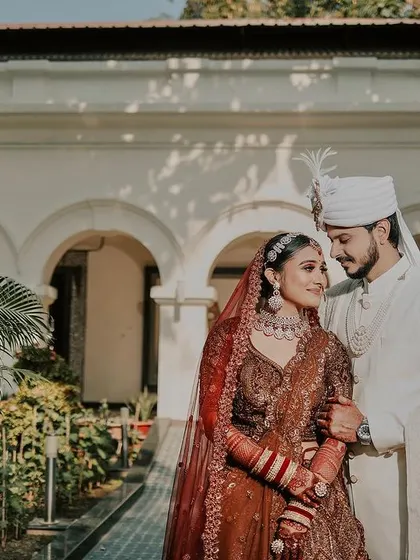 A beautiful wedding day portrait in a sunlit garden. The couple's gentle embrace and soft smiles create a romantic and timeless image of their special day.