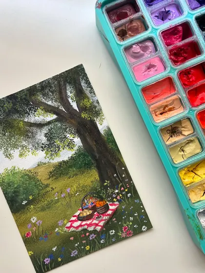 The finished picnic gouache painting next to my colorful paint palette.
