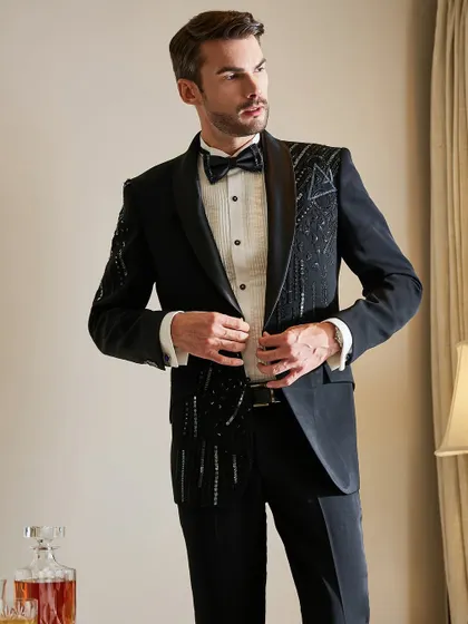 Adjusting the jacket, this shot gives a clear view of the intricate bead and sequin work on this modern black tuxedo. It's a piece designed for life's finest moments.