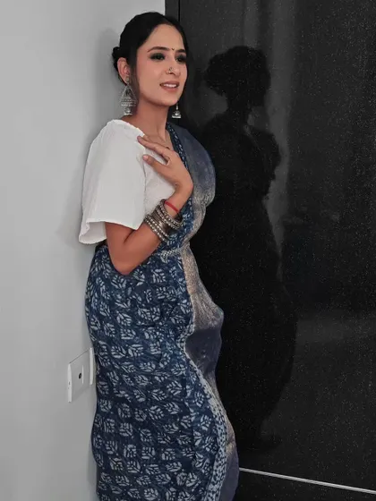 A full-length shot showing the elegant indigo saree and the subtle yet impactful makeup.