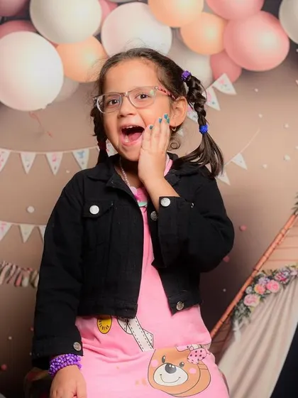 A fun and expressive shot of a young girl in front of a themed birthday backdrop. Her personality shines through in this photo.