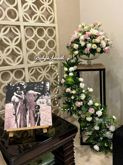 A beautiful corner from the golden jubilee celebration, featuring a vintage photo of the couple on an easel next to a cascading floral arrangement. It’s about honoring the journey.