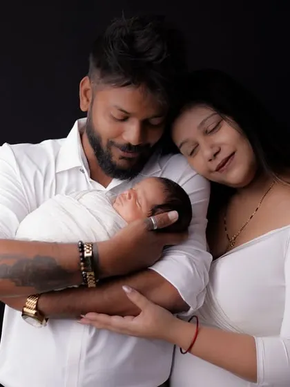 A wider shot of the family admiring their newborn. This image captures the serene and loving atmosphere of the studio session, highlighting the family's first moments together.