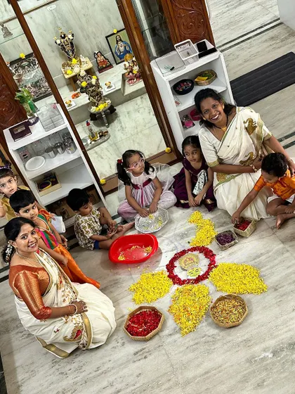 A beautiful moment of collaboration as children and teachers work together on the floor to create a flower rangoli.