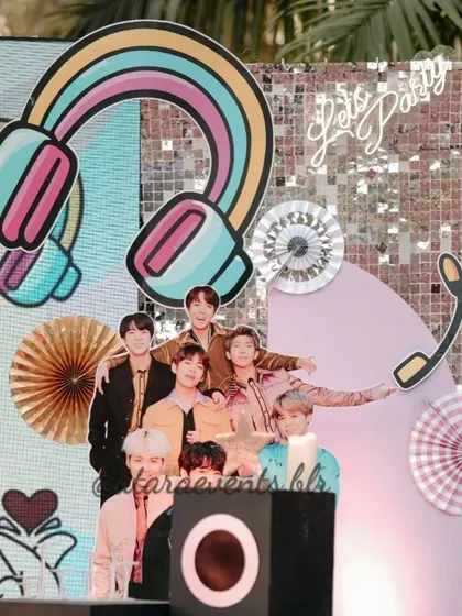 A close-up of the decor for a K-Pop party, featuring a cutout of the band BTS. The backdrop includes a sequin panel, retro headphones, and other musical motifs.