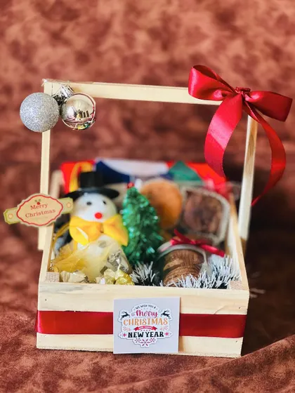 The unwrapped Christmas hamper in its wooden basket, decorated with a large red bow.