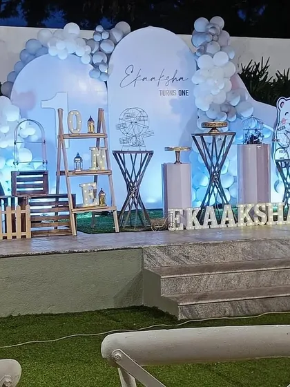 A cool winter-themed first birthday party. The decor uses a palette of white and light blue, with props like a polar bear cutout, a light-up number '1', and a photo milestone board.