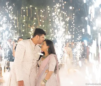 A cinematic shot of the groom kissing the bride's forehead amidst the sparklers.