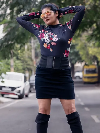 A full-frontal view of the edgy floral look. The combination of the high-neck top, corset belt, and thigh-high boots is a statement in itself.