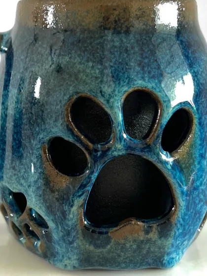 A close-up of the paw print cut-out. The rich blue glaze breaks over the edges, highlighting the details.