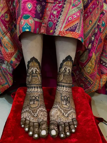 A beautiful bridal leg design featuring doli (palanquin) and peacock motifs. The pattern is intricate and tells a story, perfect for a bride's journey.