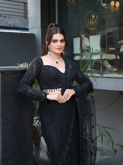 The complete look with a sleek high ponytail and an elegant black saree. This is perfect for a modern, stylish reception party.