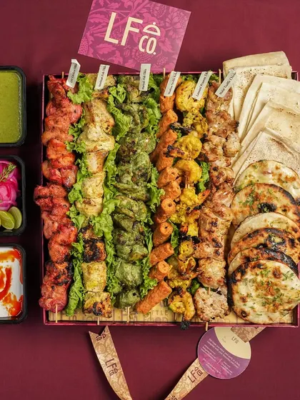 This is the non vegetarian Kebab Box, featuring a wide variety of grilled meats and vegetables. It comes complete with sides like green chutney, pickled onions, and naan, offering a full meal experience.