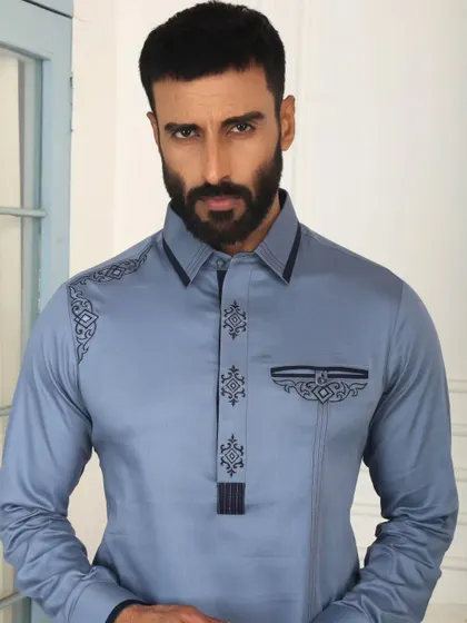 The soul of my craft lies in the details. This close-up of a sky-blue Pathani suit highlights the precise, geometric embroidery on the placket, shoulder, and pocket, a testament to the handcrafted elegance that defines every garment I create.
