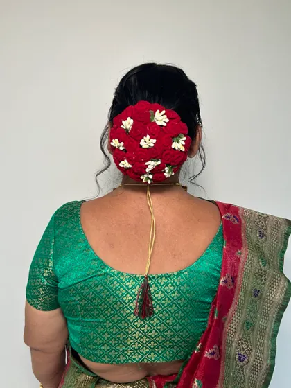 A classic Maharashtrian hairstyle for the mother of the bride. This traditional bun is decorated with a beautiful gajra of red and white flowers.