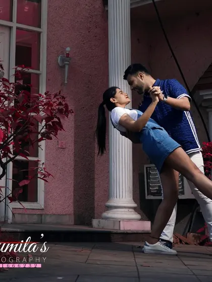 A playful dip during a pre-wedding shoot. This dynamic and fun pose captures the couple's vibrant energy against a colorful architectural backdrop.
