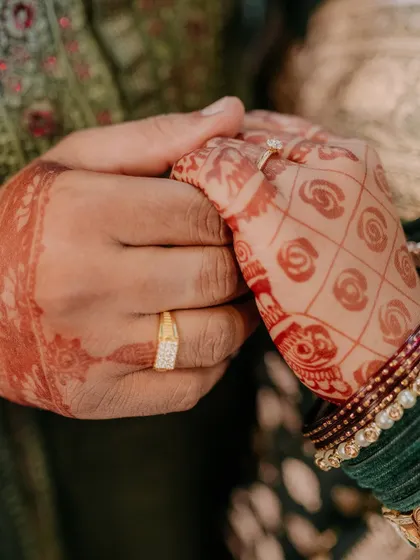 A close-up shot of the newly engaged couple's hands, showcasing their rings and the bride's beautiful mehndi. This intimate shot is all about the details.