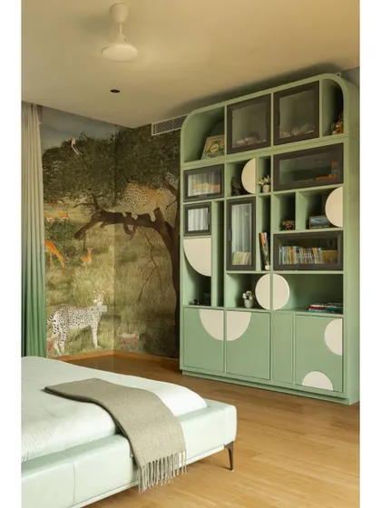 A child's bedroom from the same residential project. The room features a custom-designed green shelving unit and a beautiful, hand-painted jungle mural, creating a whimsical and personalized space.