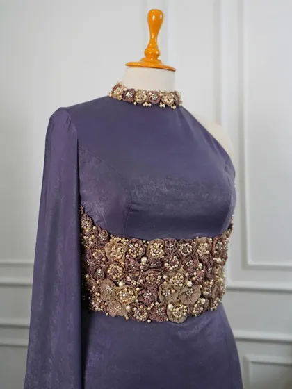 A close-up of the hand-embroidered bodice on the one-shoulder corset gown, featuring a bloom of 3D flowers and pearls that create a stunning focal point.