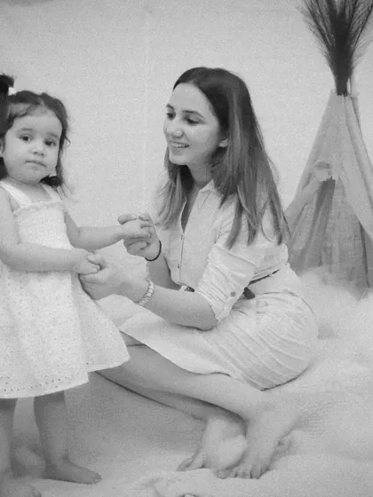 A mother and her two-year-old daughter hold hands in our studio. A beautiful black and white moment celebrating a milestone.