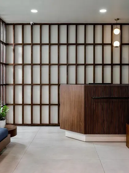 The reception area at the Artem office is designed to be warm and welcoming, moving away from typical corporate aesthetics. We used a wooden reception desk and a slatted wood feature wall, complemented by deep blue seating and indoor plants, to create an inviting first impression.