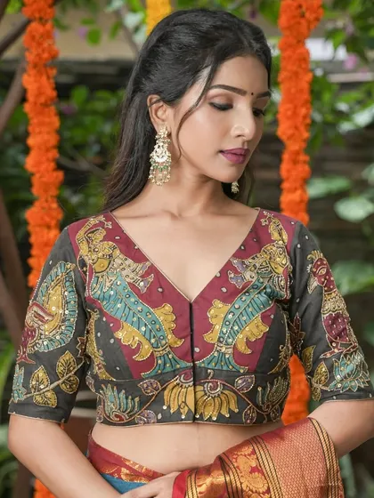 A model wears large, ornate chandbali earrings with multiple pearl drops. They perfectly complement her Kalamkari blouse, creating a look that is both artistic and regal.