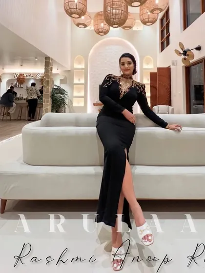 A client looking absolutely glamorous in a custom black gown for her birthday. The gown features a thigh-high slit and stunning gold embroidery on the shoulders and neckline.
