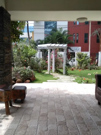 From the porch of this villa, the view opens up to a beautifully landscaped garden with a pathway leading to a white arch, creating an inviting journey through the space.