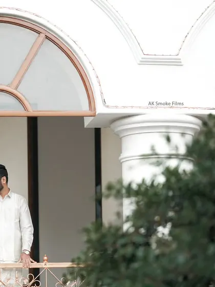 A wide shot of a couple on a balcony during their Pollachi wedding, using architectural elements to frame the scene.