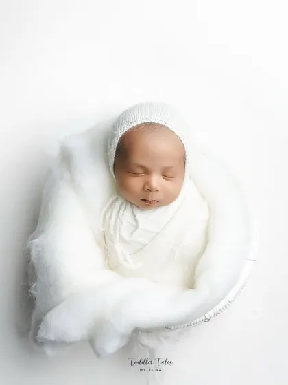 Wrapped in pure white, this 18-day-old newborn rests peacefully. My minimalist newborn photography focuses on their serene beauty and delicate features, creating a clean and timeless portrait.