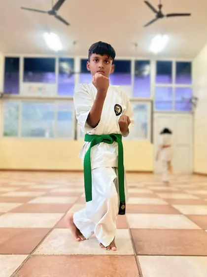 A young student demonstrates a strong Neko Ashi Dachi (cat stance), a fundamental posture in karate that builds balance and readiness.
