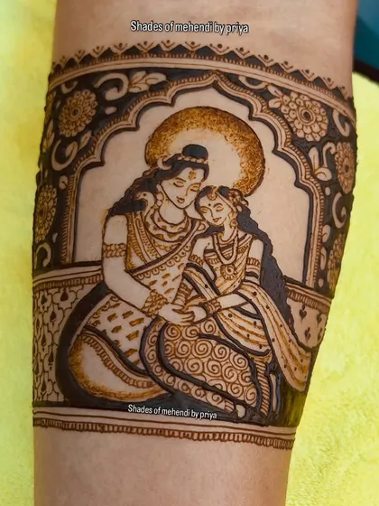 A close-up of a Radha-Krishna portrait on the arm, framed by an arch. The shading gives the figures a three-dimensional feel.