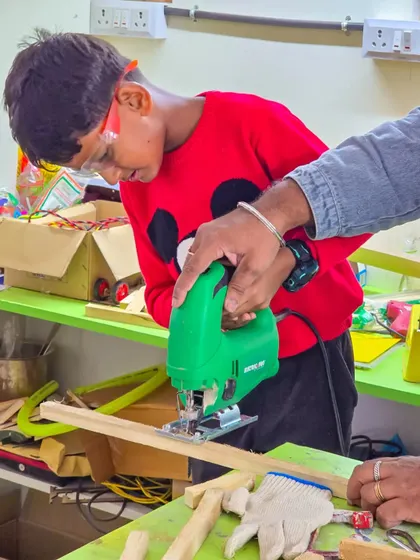 A student carefully guides a jigsaw to cut a piece of wood for his project. We prioritize one on one attention, especially when kids are learning to use power tools for the first time.