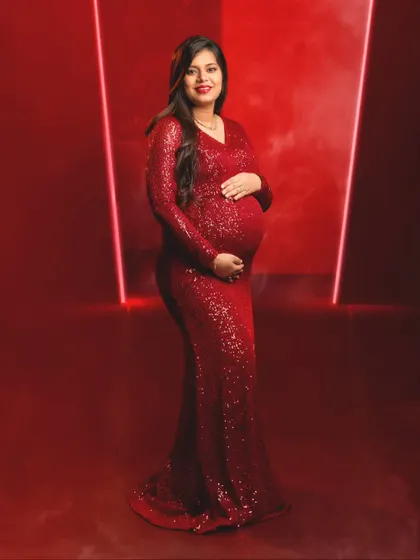A classic, smiling portrait of a mom-to-be, radiant and confident in her sparkling red dress.