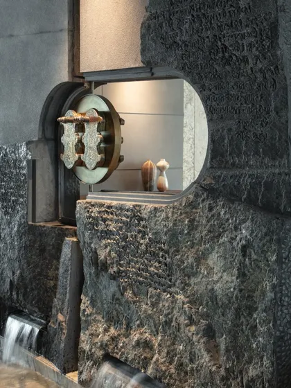 A close-up of the water feature's 'Khadau' centerpiece. The intricately detailed brass sandals, a symbol of sanctity, appear to float within the stone, creating a moment of focused reverence and artistry.