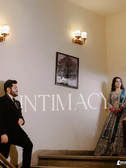 A stylish portrait of Nikhil and Khushbu on a staircase, titled 'Intimacy', capturing a quiet moment between the couple.
