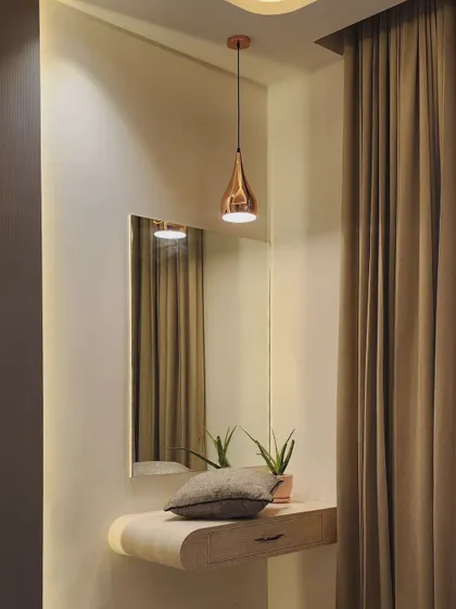 Little corners in a bedroom deserve attention too. This simple dressing nook is made special with a curved floating console, a statement copper pendant light, and elegant floor-to-ceiling curtains.