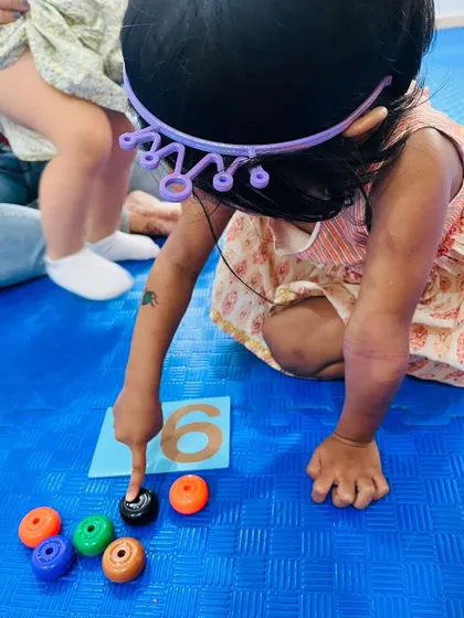 Counting out six rings to match the numeral, this child is learning about one-to-one correspondence in a playful way.