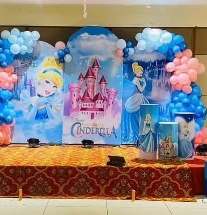 A grand stage setup for a Cinderella-themed birthday party, with three large backdrops featuring the princess and her castle.