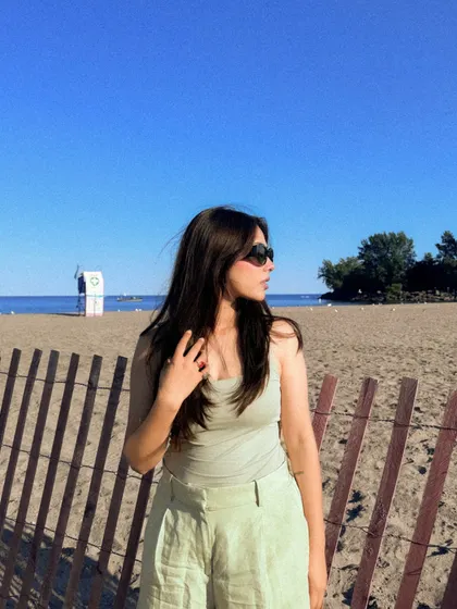 Golden hour at the beach, wearing a simple tank top and linen shorts.