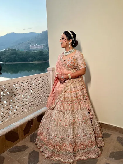 A full-length shot of Varija in her beautiful peach lehenga. The makeup is soft and romantic, perfect for a destination wedding.