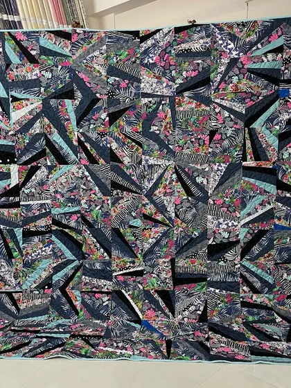 A "strip pieced" quilt with a chaotic, modern energy. Strips of floral and animal print fabric are sewn together improvisationally to create a unique and abstract design.
