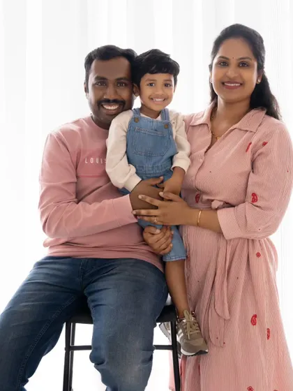A classic family portrait of three, with everyone sharing a happy smile. The coordinated pink and denim outfits look great together.